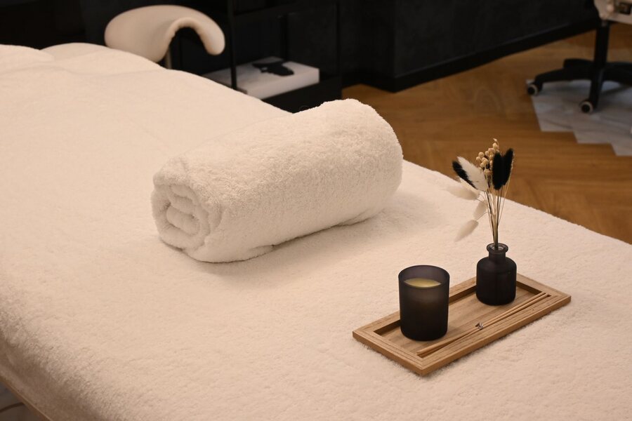 A cream massage bed with a rolled towel and a small candle tray